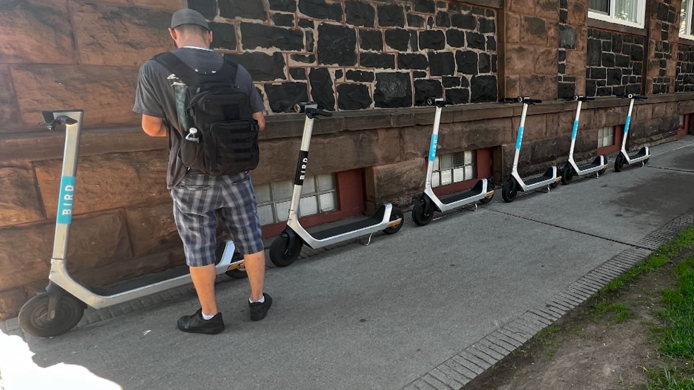Motorized scooters lined up along a sidewalk