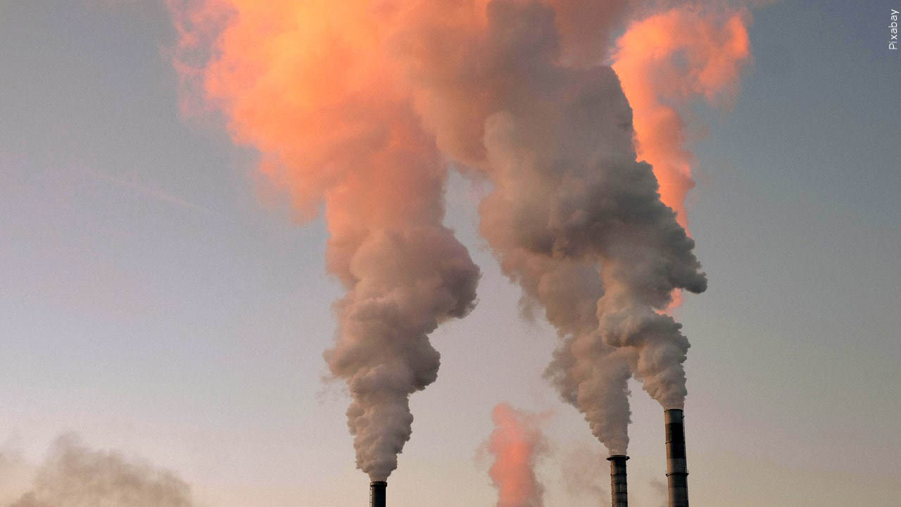 smoke or steam coming out of stacks over a blue sky