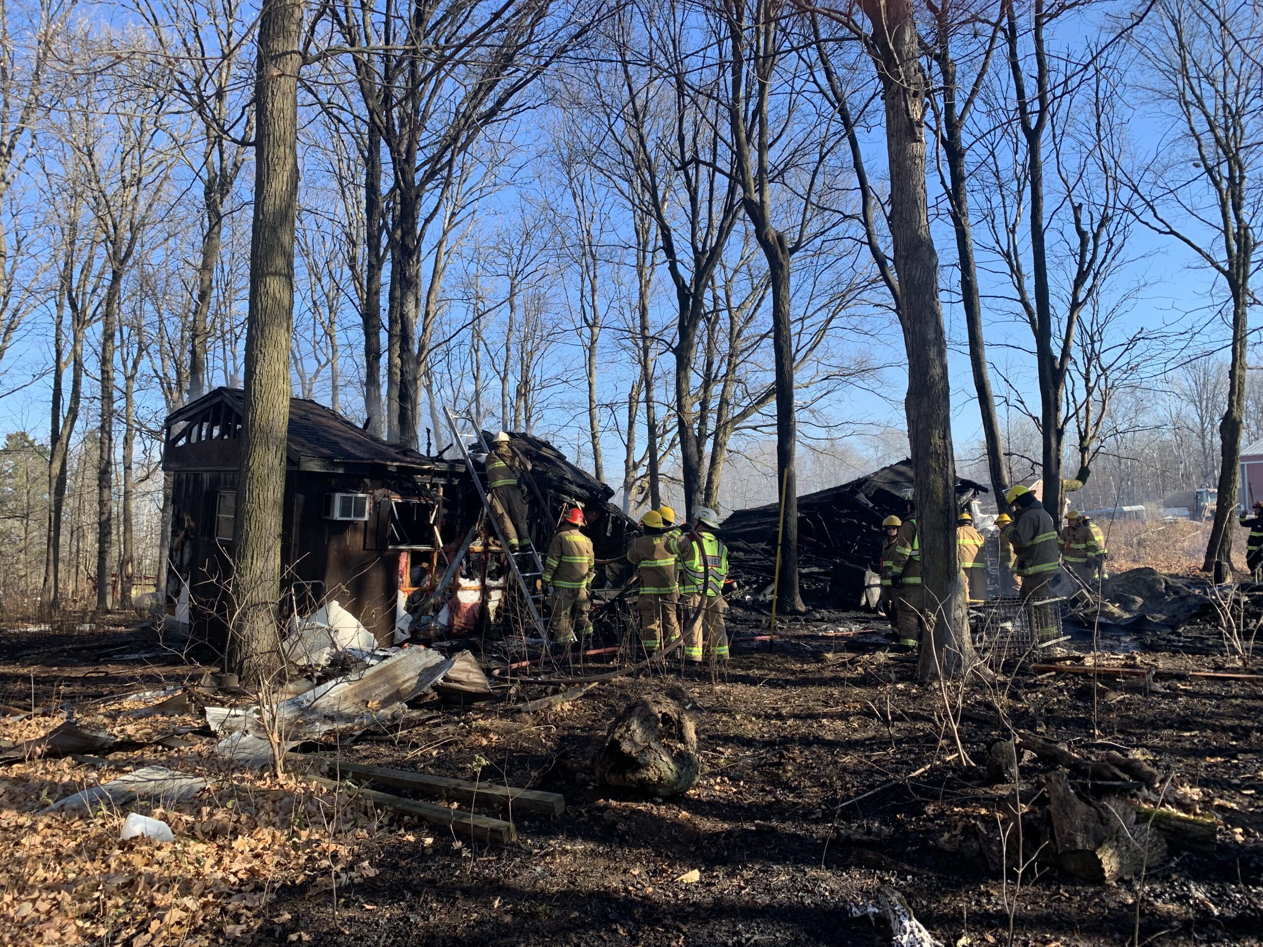 Firefighters gather outside a burned home