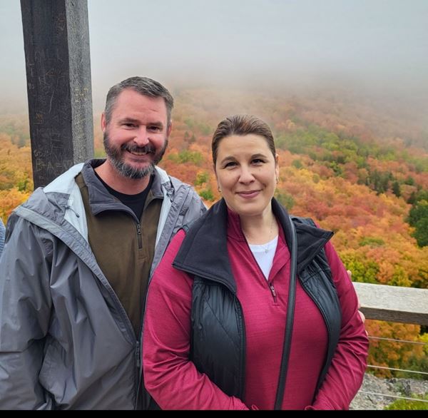 view of couple at an overlook with fall colors behind
