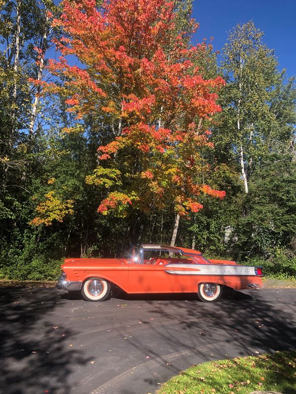 an orange 1956 XM Turnpike Cruiser Concept car in front of maple tree