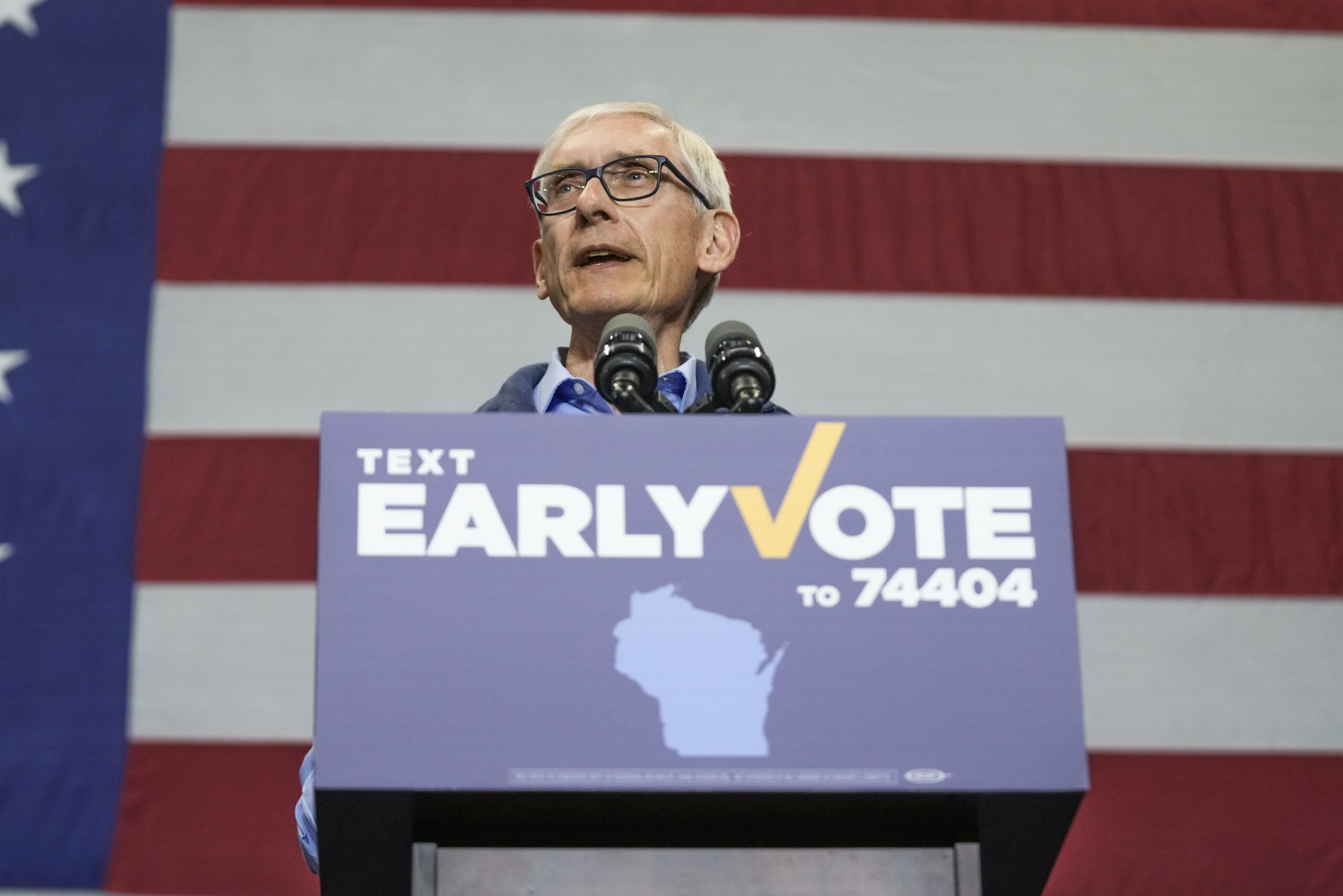 Gov. Tony Evers speaks behind a Early Vote podium