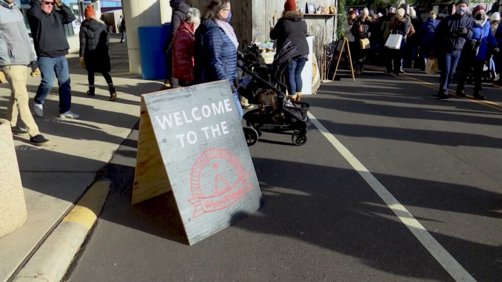 Entrance sign to the Duluth Winter Village with people walking