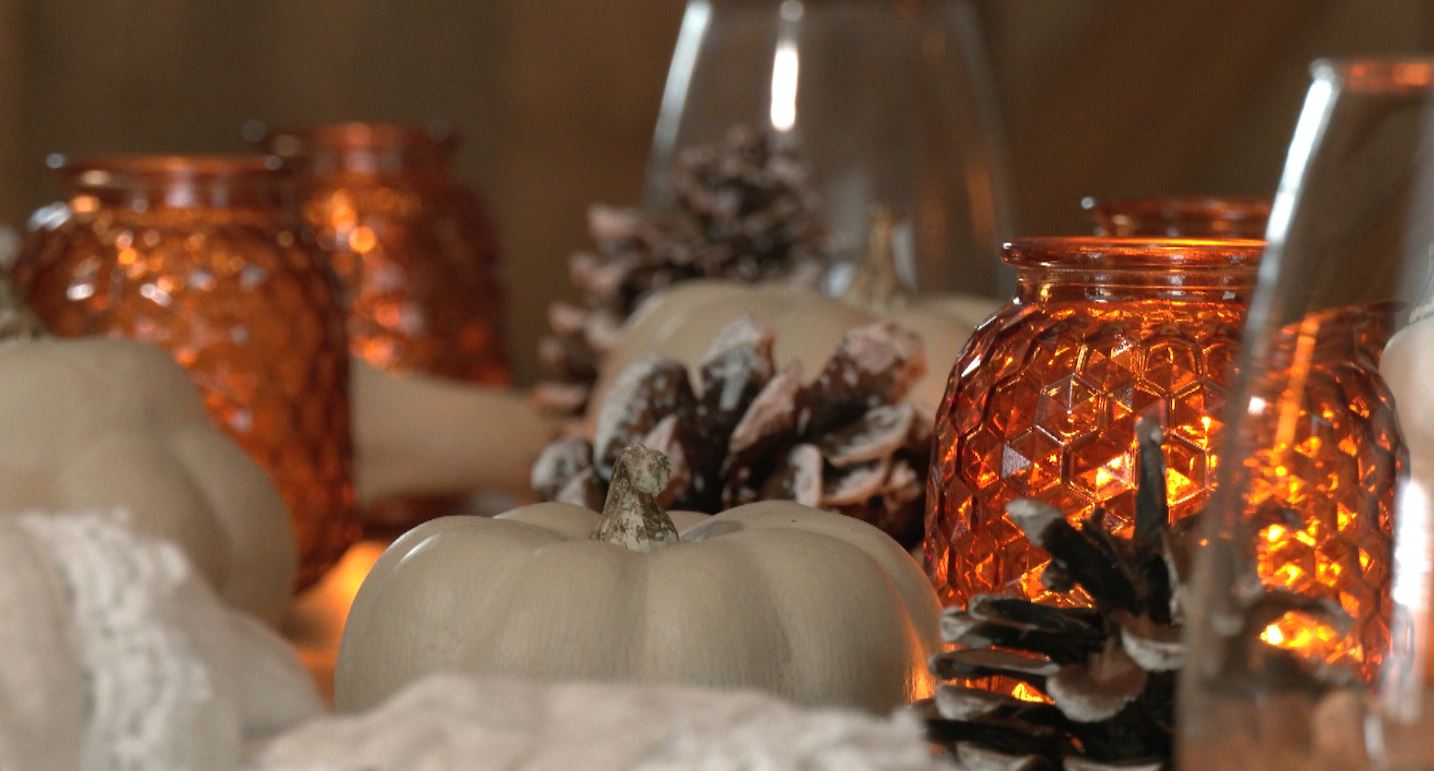 Candles, pumpkins, and pinecones on a table