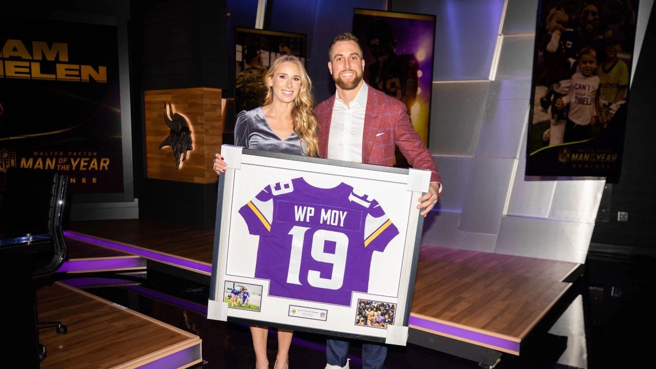 Picture of Adam Thielen with his wife Caitlin, holding a Walter Payton Man of the Year picture
