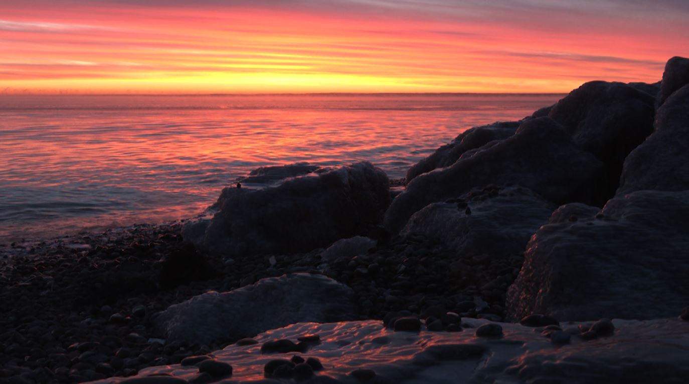A pink and yellow sunrise on the shore of Lake Superior