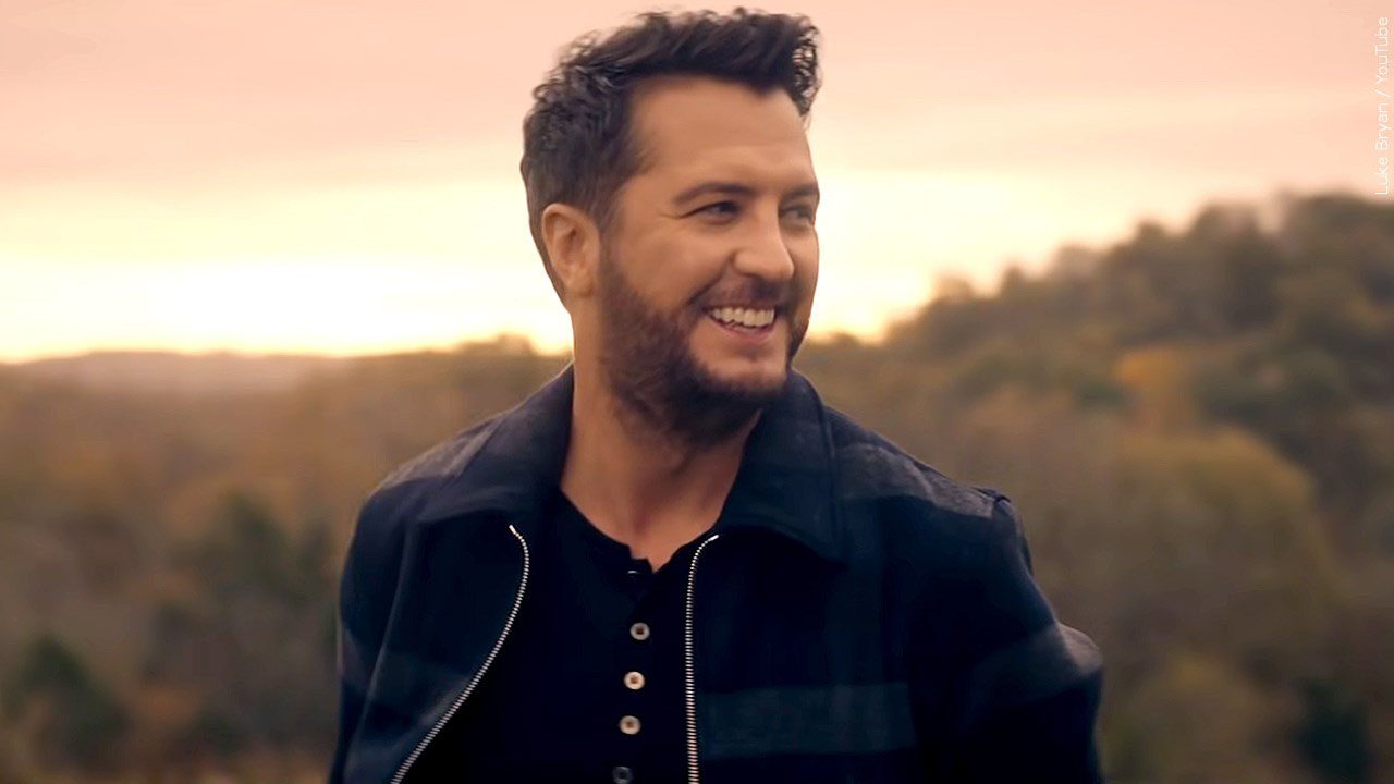 picture of country singer Luke Bryan looking to his left with a sunset behind him.