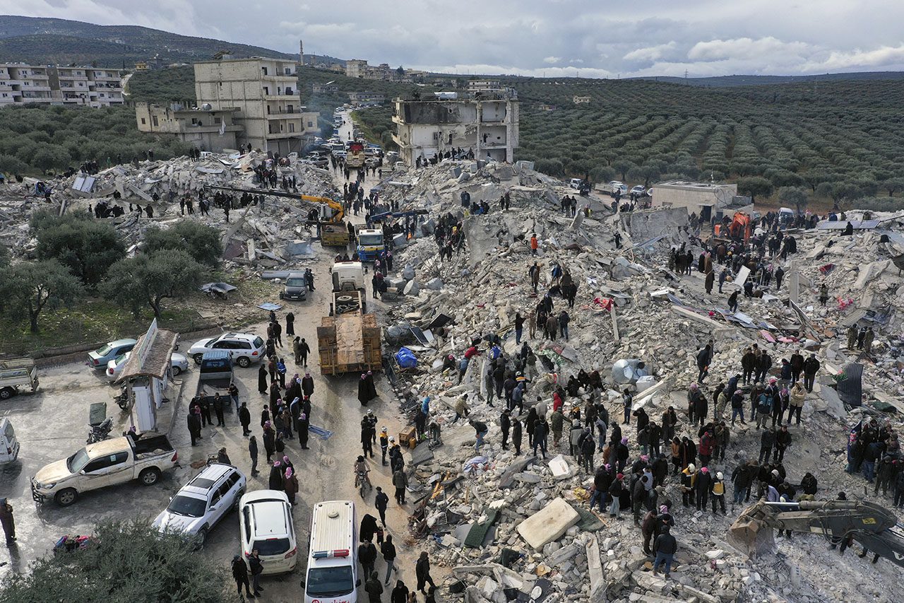 Hundreds of people gather on rubble searching for survivors in earthquake on Syria / Turkey border.