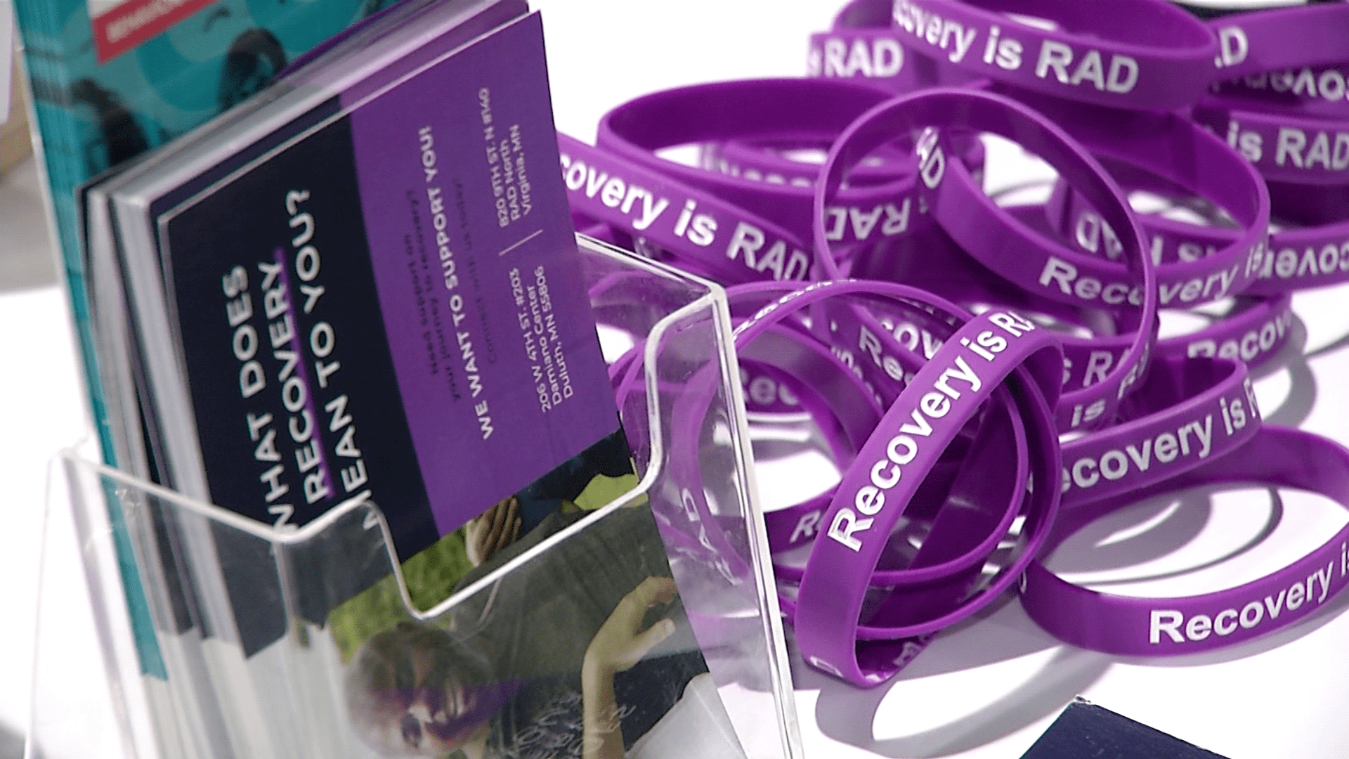 Table display with "Recovery is Rad" bracelets and brochures.