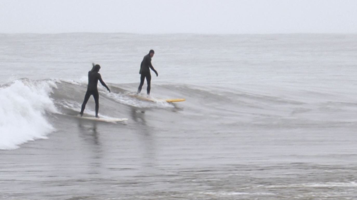 Two surfers ride a wave on Lake Superior