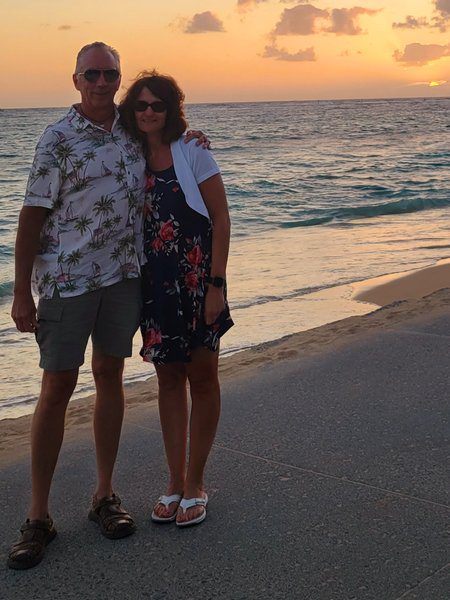 A couple standing on Waikiki Beach with the fading, golden sunset behind them.