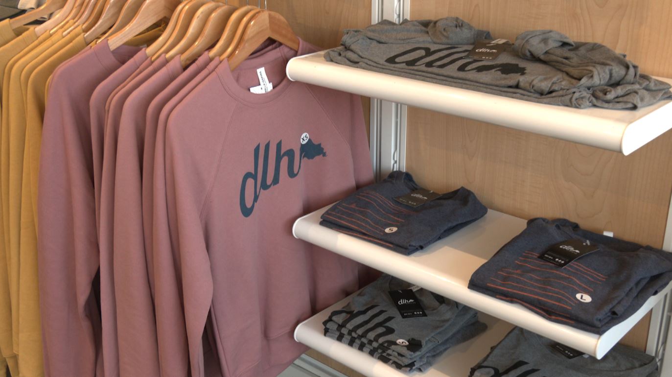 A rack of sweatshirts and shelves of T-shirts at DLH Clothing