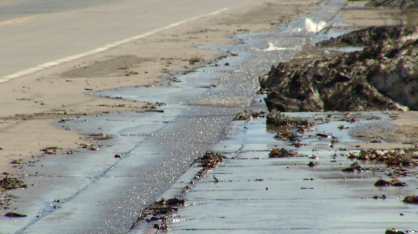 Melting snow flows toward a storm drain