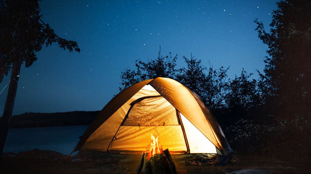 A tent lit up under the night sky