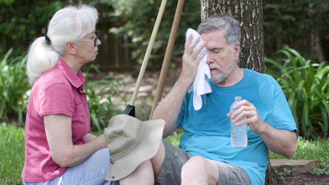 A man and a woman sitting trying to cool down in the heat.