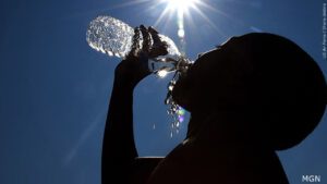person drinking bottled water with blue sky and sunshine
