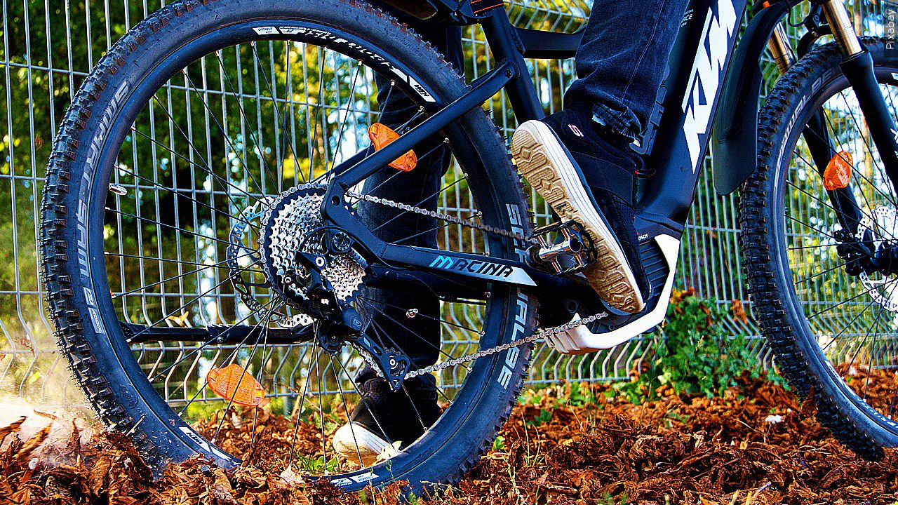 The wheels of a bicycle riding through fall leaves