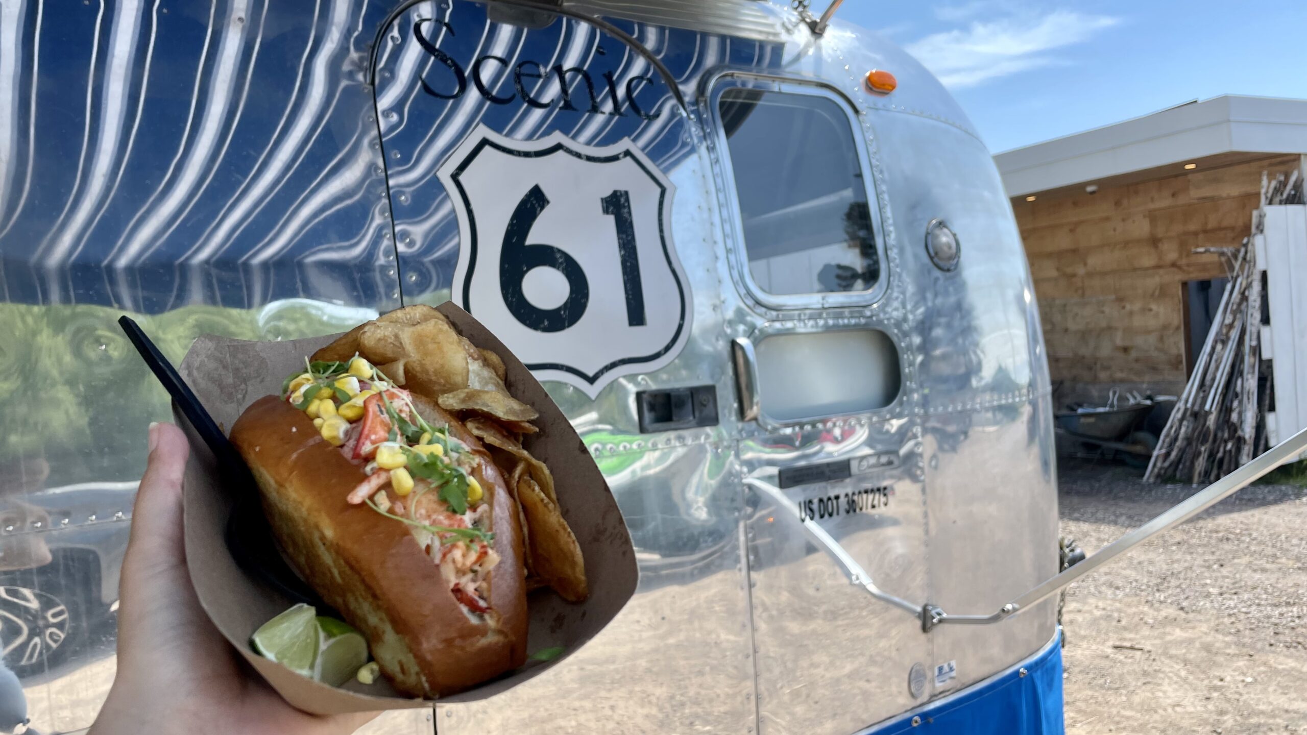 A lobster roll in front of the Scenic 61 food trailer