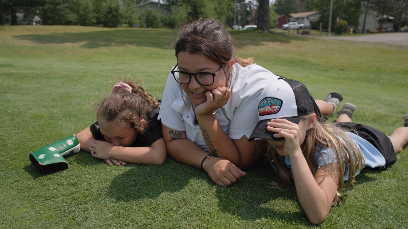 Junior golfers Esme and Gianna help instructor Kaitlin Zenner assess a putt.