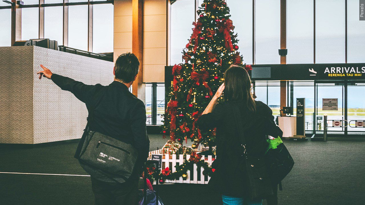 Two people in an airport decorated for the holidays
