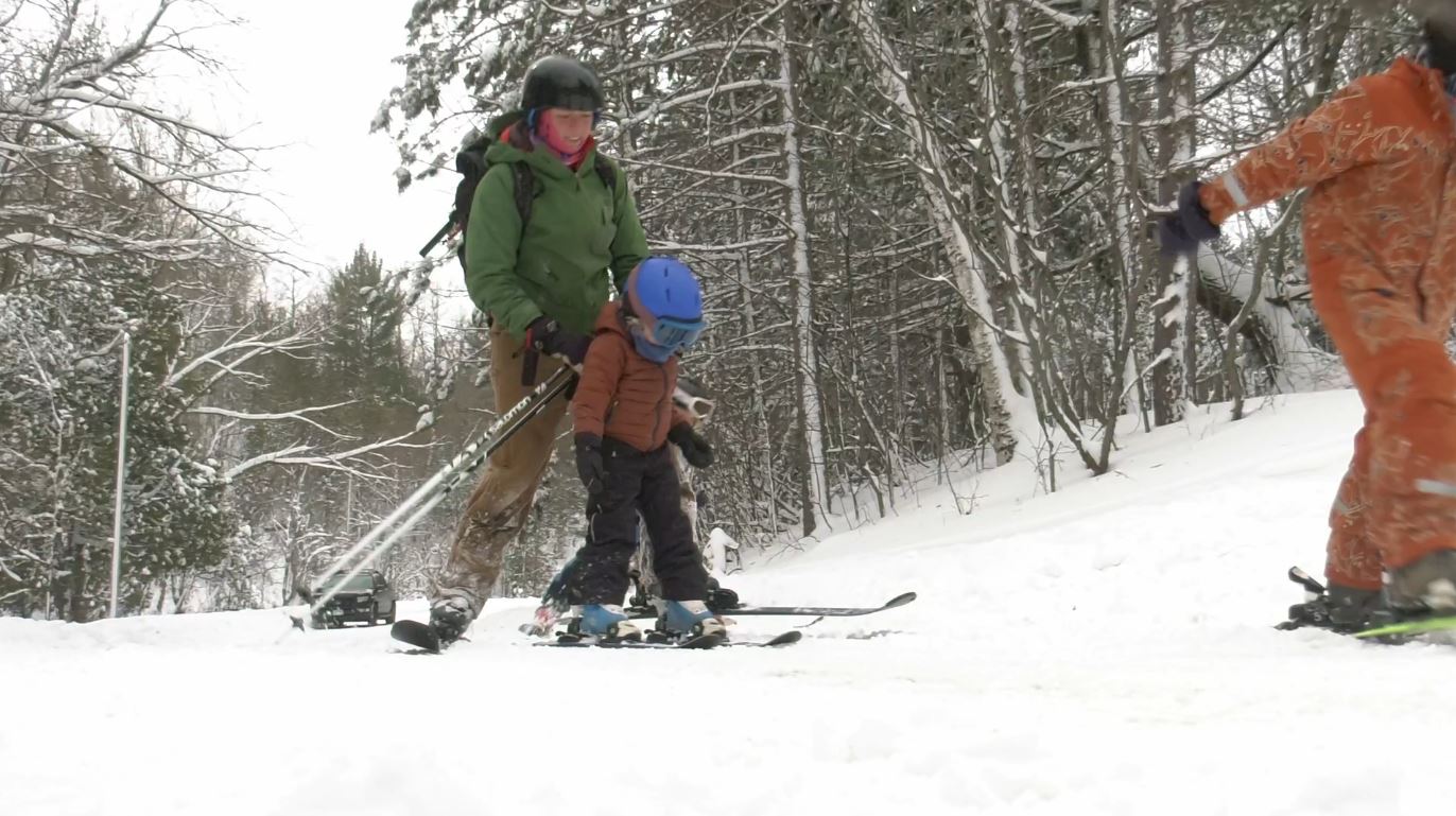 An adult and a few kids take off on skis at Chester Park