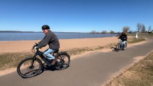 Two people ride bikes along the shore of the Chequamegon Bay