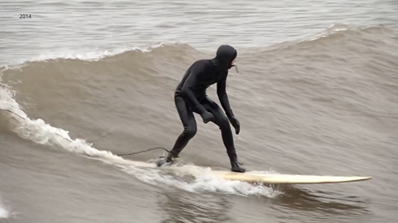 A surfer rides a Lake Superior wave in April 2014